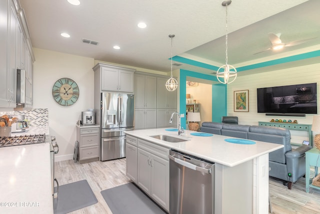 kitchen with stainless steel appliances, sink, an island with sink, light hardwood / wood-style flooring, and pendant lighting