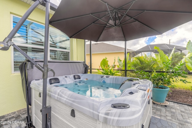 view of patio / terrace featuring a hot tub and glass enclosure