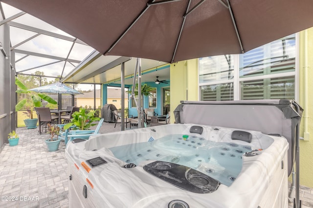 view of patio / terrace featuring ceiling fan, a lanai, and a hot tub