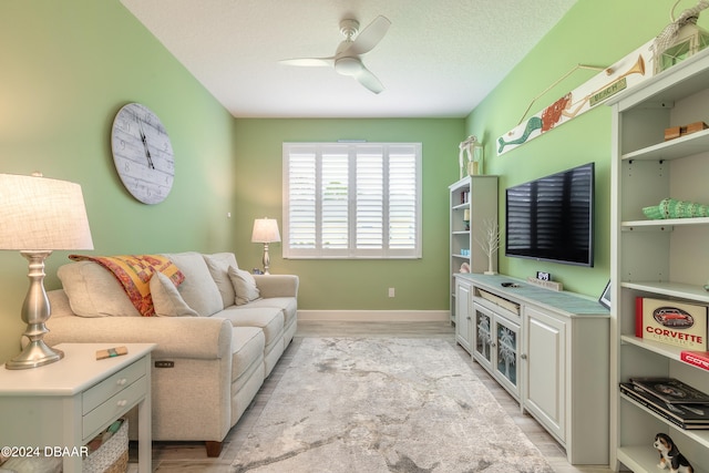 living room with ceiling fan, a textured ceiling, and light hardwood / wood-style flooring