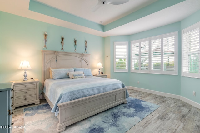 bedroom with ceiling fan, multiple windows, and light hardwood / wood-style flooring