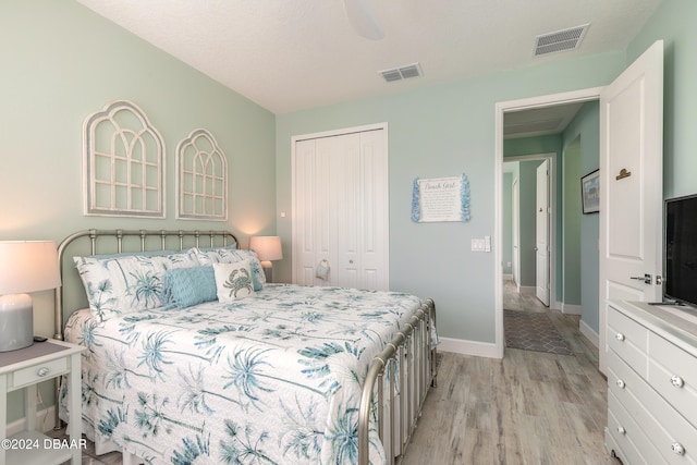 bedroom with light hardwood / wood-style floors, ceiling fan, and a closet