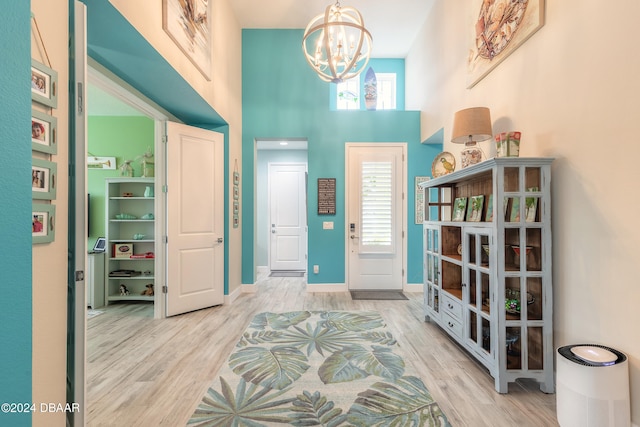 foyer featuring light wood-type flooring, an inviting chandelier, and a towering ceiling