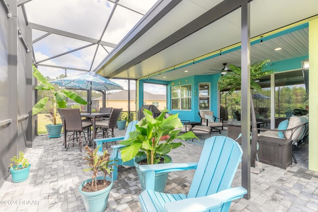 view of patio featuring glass enclosure, an outdoor hangout area, and ceiling fan