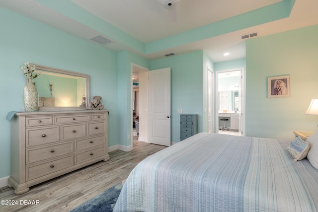 bedroom with ensuite bathroom and light wood-type flooring