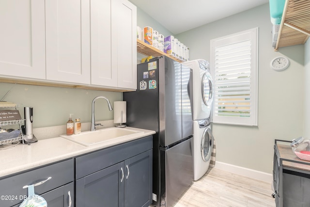 clothes washing area with stacked washer and dryer, sink, and light hardwood / wood-style floors