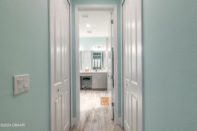 hallway with light hardwood / wood-style flooring and a textured ceiling