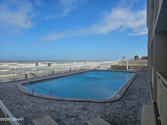 view of swimming pool with a water view and a beach view