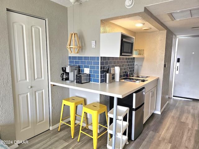 kitchen featuring appliances with stainless steel finishes, tasteful backsplash, sink, wood-type flooring, and white cabinets