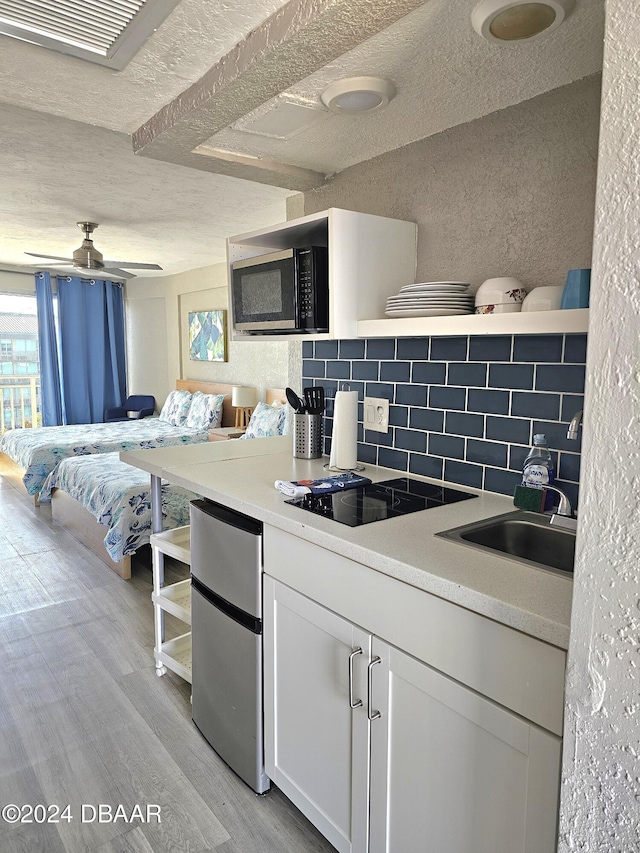 kitchen featuring white cabinets, decorative backsplash, ceiling fan, a textured ceiling, and light hardwood / wood-style floors