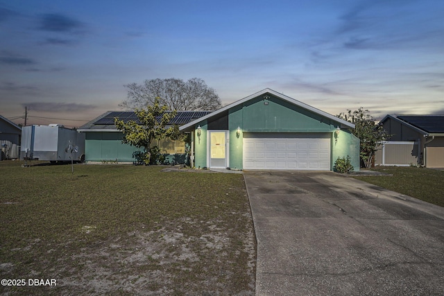 ranch-style home featuring a yard, solar panels, and a garage