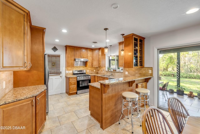 200 W Washington Ave, Deland, FL 32720 - kitchen with appliances with stainless steel finishes, a sink, a peninsula, under cabinet range hood, and decorative backsplash