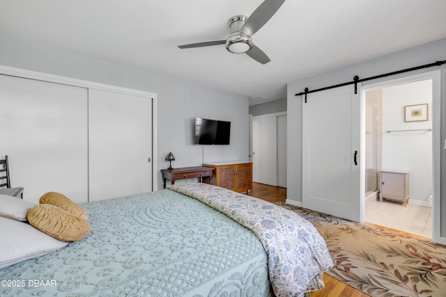 200 W Washington Ave, Deland, FL 32720 - bedroom featuring multiple closets, a barn door, wood finished floors, a ceiling fan, and connected bathroom