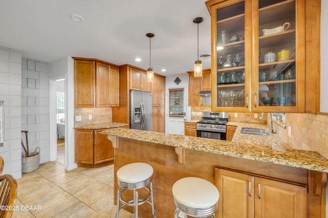 200 W Washington Ave, Deland, FL 32720 - kitchen with stainless steel appliances, a sink, under cabinet range hood, light stone counters, and glass insert cabinets