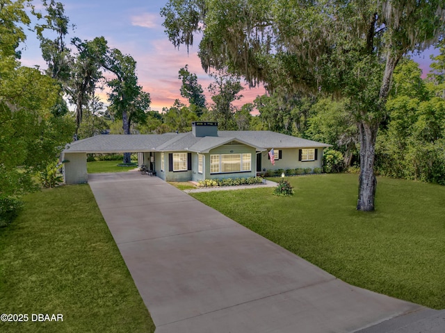 200 W Washington Ave, Deland, FL 32720 - ranch-style home featuring driveway, a front yard, a chimney, a carport, and view of scattered trees
