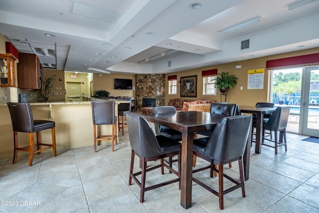 dining room with french doors, a fireplace, and a raised ceiling