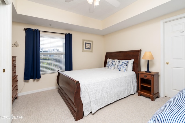 carpeted bedroom featuring a tray ceiling and ceiling fan