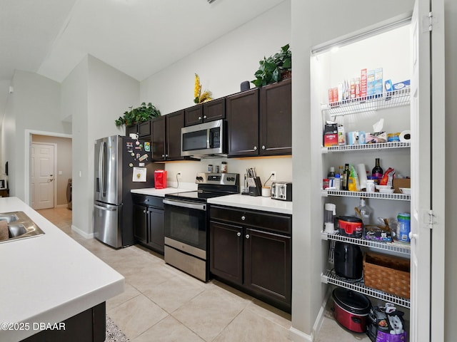 1354 Vandalia Ave SE, Palm Bay, FL 32909 - kitchen featuring appliances with stainless steel finishes, light tile patterned floors, light countertops, dark brown cabinetry, and lofted ceiling
