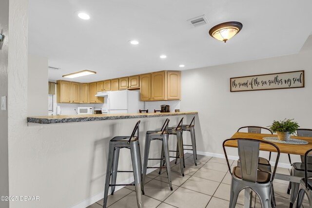 3800 S S Atlantic Ave Unit 105, Daytona Beach Shores, FL 32118 - kitchen with white appliances, a breakfast bar area, baseboards, light tile patterned floors, and recessed lighting
