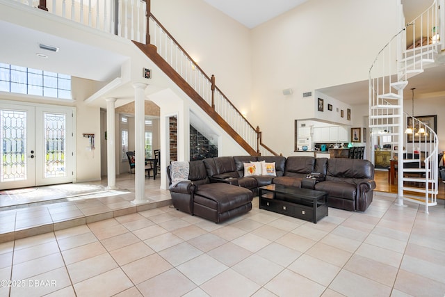 living room with decorative columns, light tile patterned flooring, stairs, and french doors