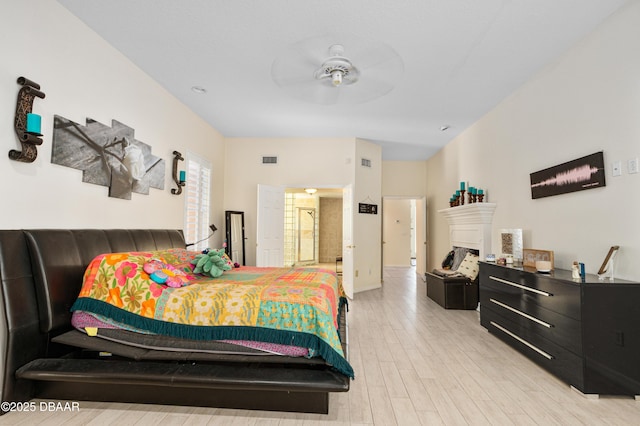 bedroom featuring a fireplace, visible vents, light wood finished floors, and ceiling fan