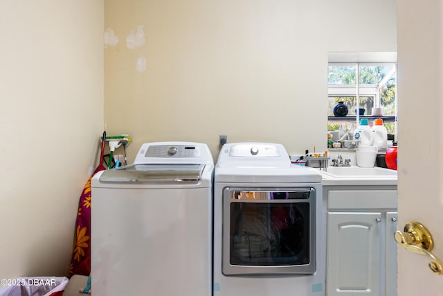 laundry room with cabinet space, washer and dryer, and a sink