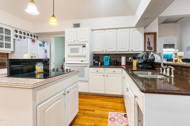 kitchen with visible vents, a sink, white cabinetry, white appliances, and a peninsula