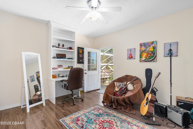 office area with a ceiling fan, wood finished floors, baseboards, and a textured ceiling