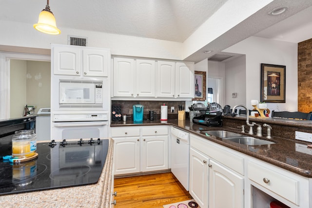 kitchen featuring white appliances, visible vents, light wood-style flooring, a sink, and white cabinets