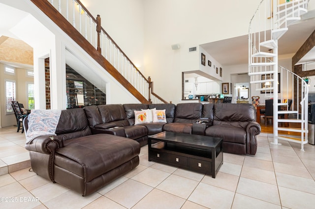 living room featuring tile patterned floors, stairway, visible vents, and a towering ceiling