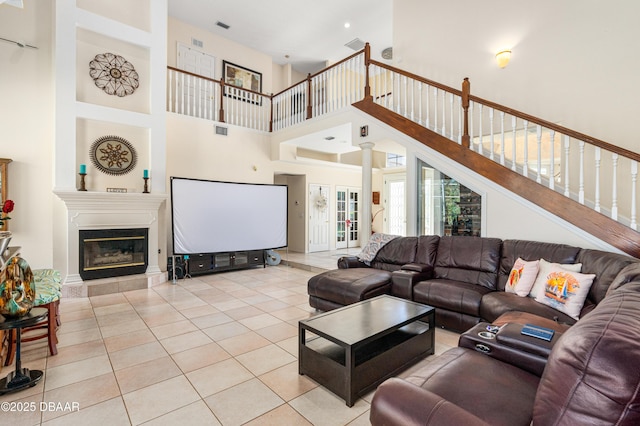 living area with a glass covered fireplace, light tile patterned floors, visible vents, and decorative columns