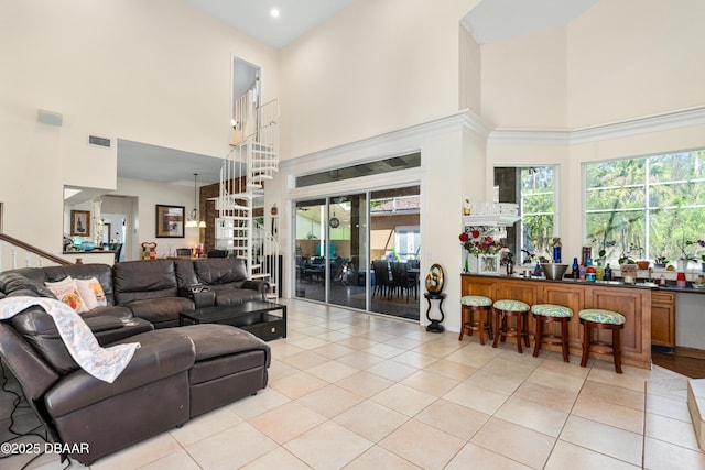 living room featuring bar area, a high ceiling, light tile patterned floors, and visible vents