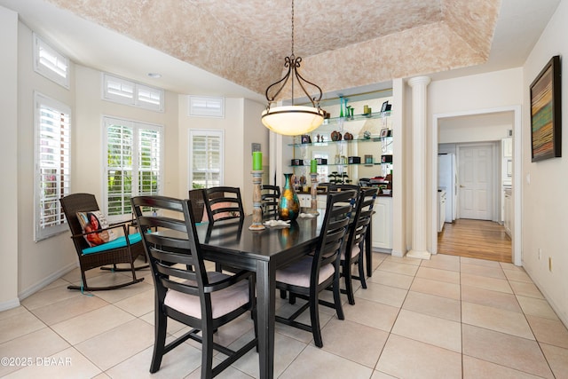 dining room with light tile patterned floors, baseboards, and a raised ceiling