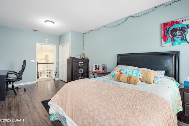 bedroom featuring visible vents, baseboards, a closet, and wood finished floors