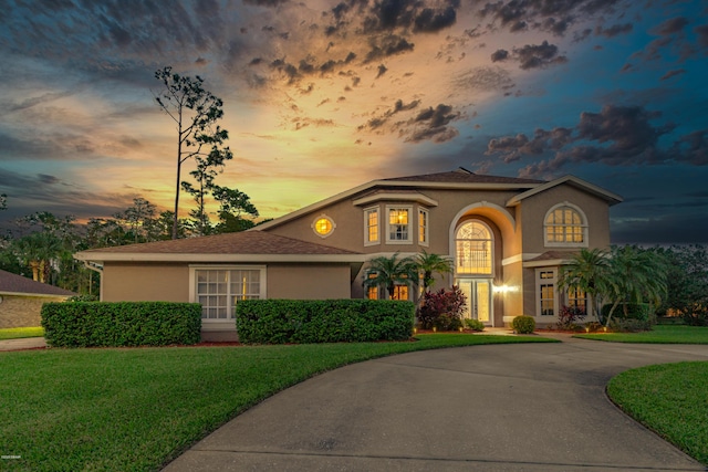 mediterranean / spanish house with stucco siding, a front yard, driveway, and french doors