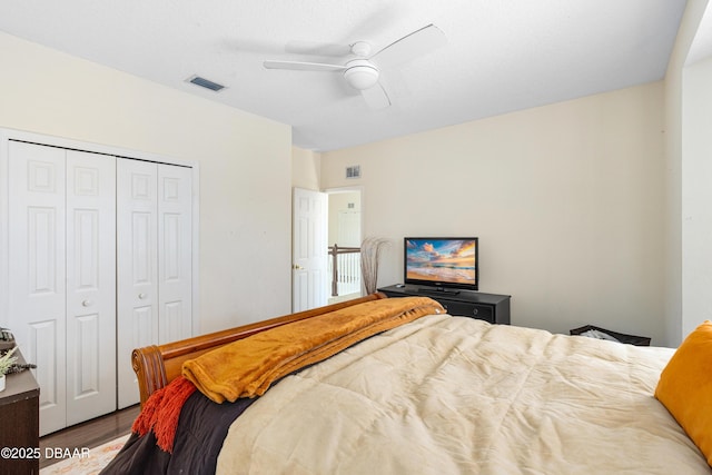 bedroom featuring ceiling fan, a closet, visible vents, and wood finished floors