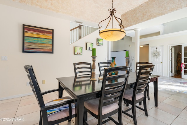 dining room featuring light tile patterned floors, baseboards, and decorative columns