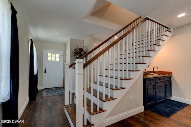 entryway featuring recessed lighting, stairs, dark wood-type flooring, and baseboards