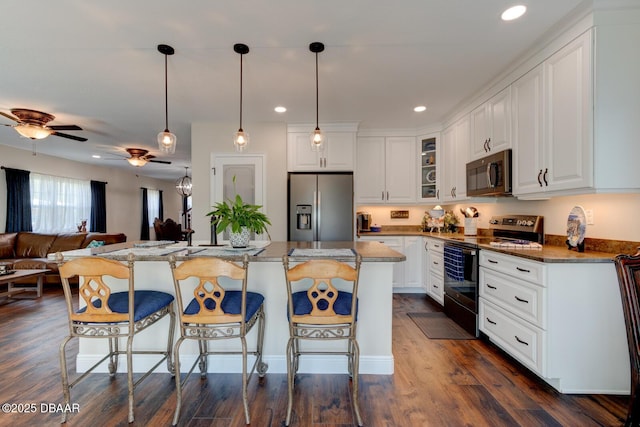 kitchen with a ceiling fan, a kitchen breakfast bar, white cabinetry, appliances with stainless steel finishes, and glass insert cabinets