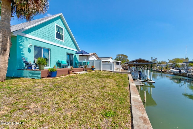 exterior space featuring a yard, a water view, boat lift, and fence