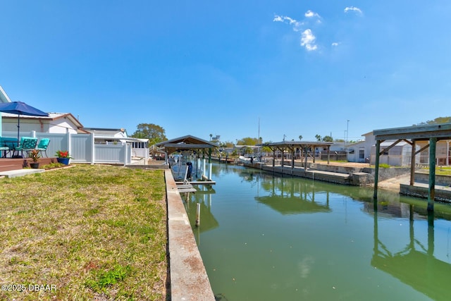 view of dock with boat lift, fence, a yard, and a water view