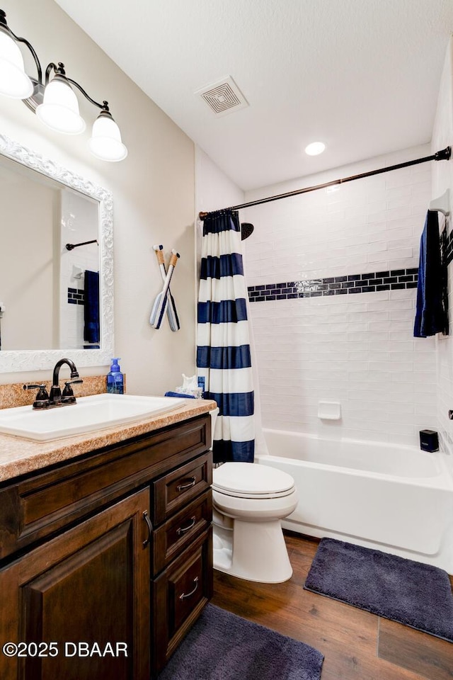 full bathroom featuring vanity, wood finished floors, visible vents, shower / tub combo, and toilet