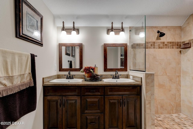 bathroom with a sink, a textured ceiling, walk in shower, and double vanity