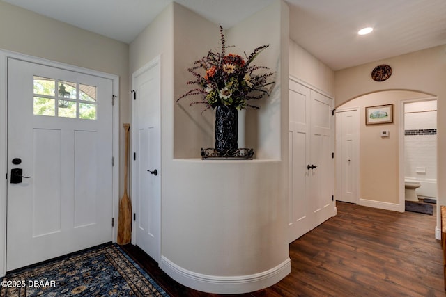 foyer entrance with dark wood finished floors, recessed lighting, baseboards, and arched walkways