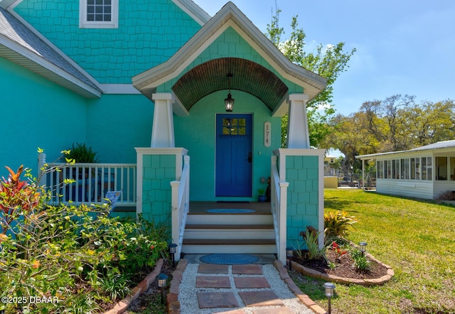 doorway to property with a lawn and covered porch