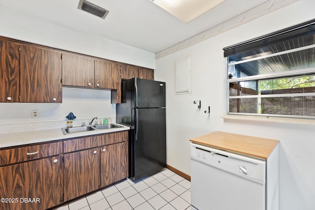 kitchen with black fridge, white dishwasher, sink, and light tile patterned floors