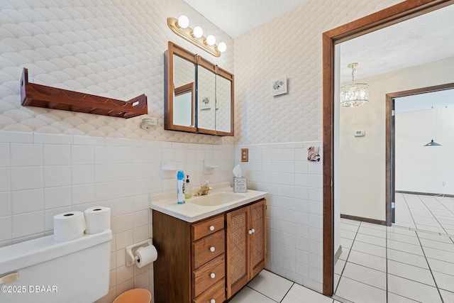 bathroom featuring tile walls, tile patterned flooring, vanity, toilet, and a textured ceiling