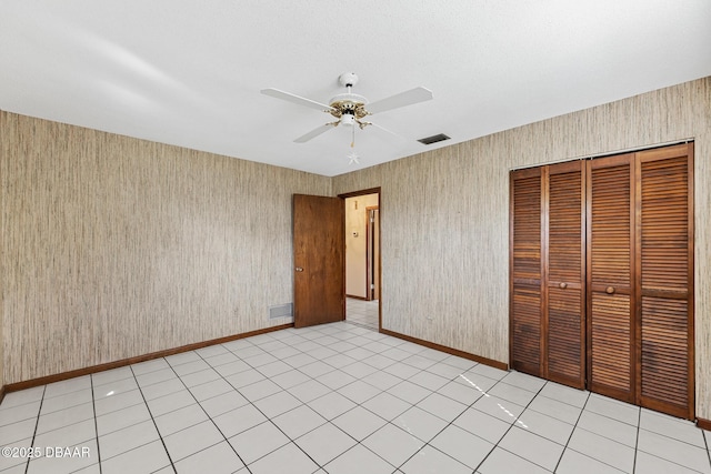 unfurnished bedroom with light tile patterned flooring, ceiling fan, and a closet