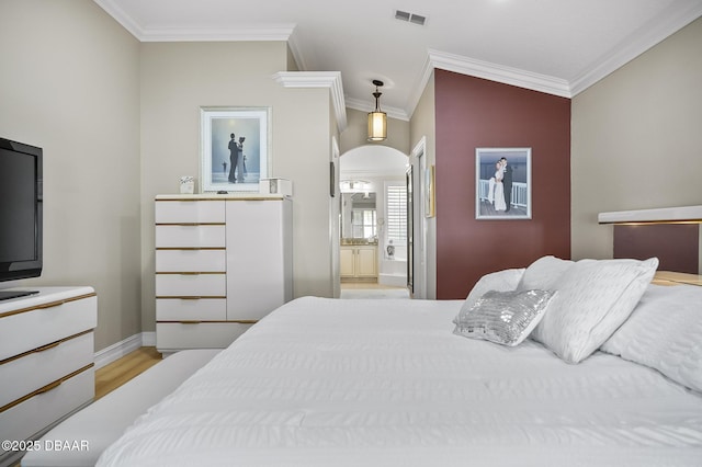 bedroom featuring vaulted ceiling, ensuite bathroom, light hardwood / wood-style flooring, and ornamental molding