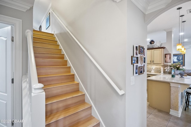 stairway featuring crown molding, tile patterned flooring, and sink